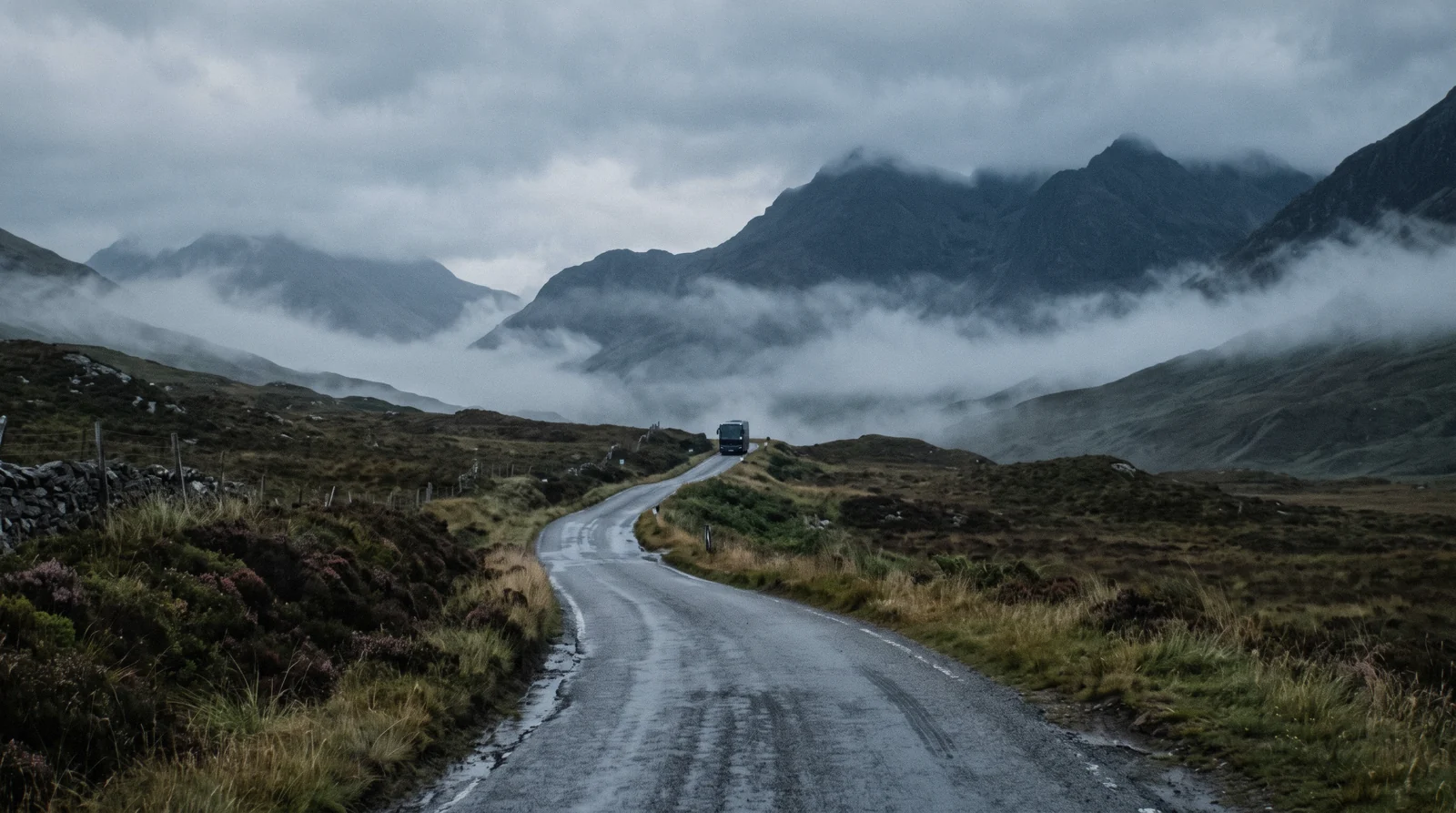 A single-track road running north between Highland peaks under low cloud, the landscape the long coach day trips from Edinburgh drive through on the way to Glencoe and Loch Ness