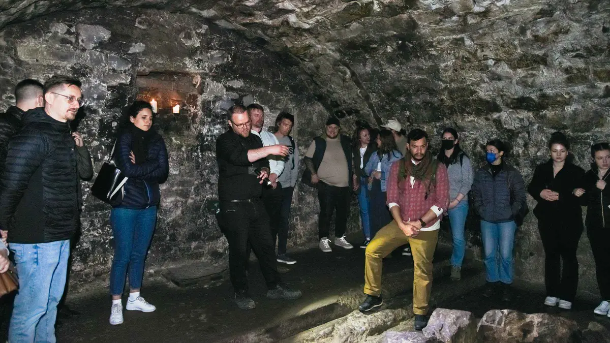Guide holding a candle in a dimly lit South Bridge chamber on an Edinburgh underground vaults tour