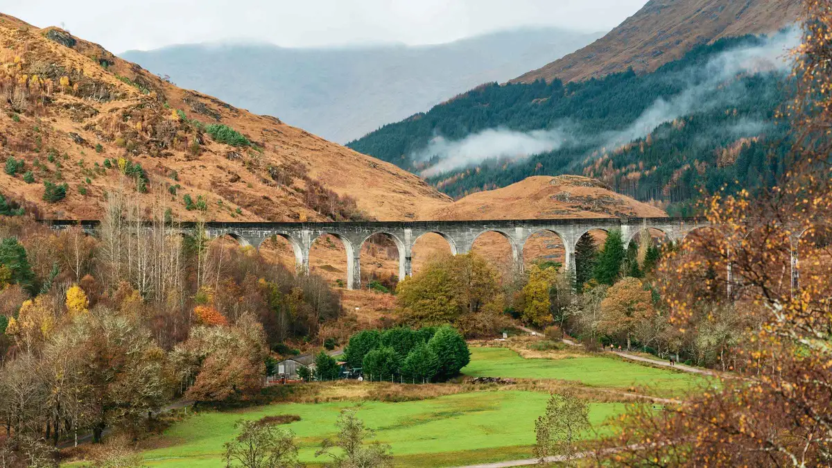 Coach passengers at the Glenfinnan Viaduct viewpoint above Loch Shiel on a Highlands day trip from Edinburgh