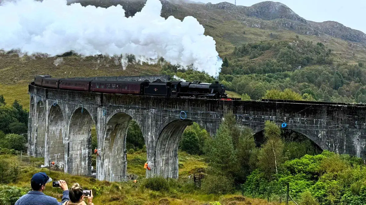 Hairy Coo coach group photographing the Glenfinnan Viaduct on a Highlands day trip from Edinburgh