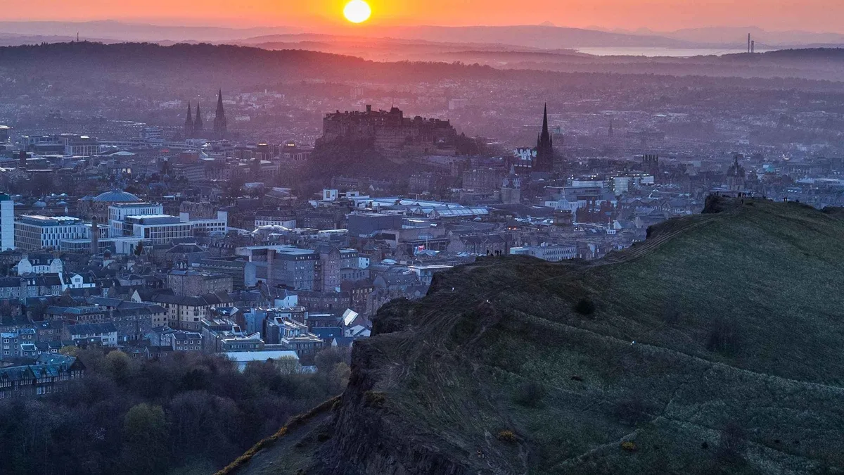 Hikers on the summit of Arthur's Seat at sunset above Edinburgh on a guided small-group hike