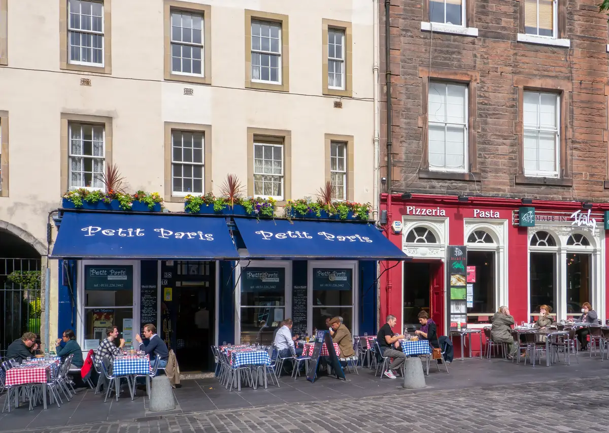 Restaurants and cafes along the Grassmarket in Edinburgh with tables out on the pavement, part of the eating-out scene two streets off the Royal Mile