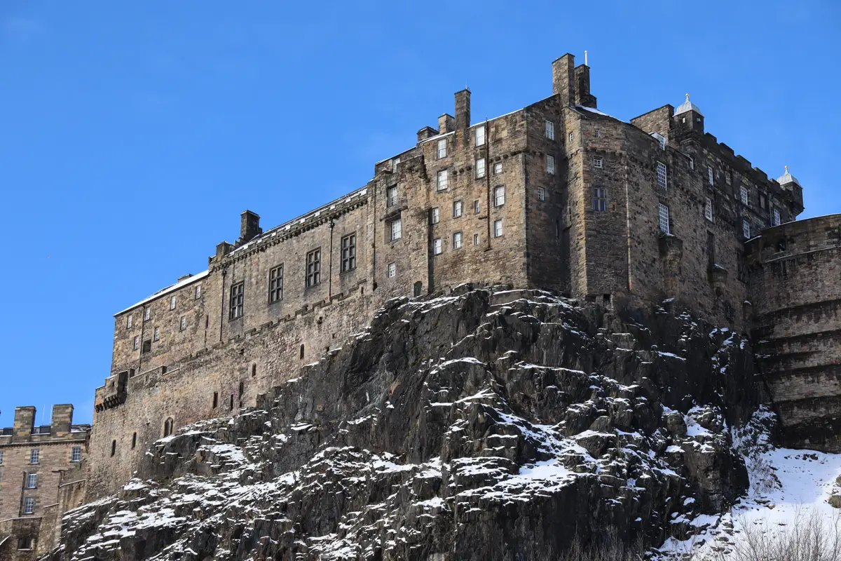 The south side of Edinburgh Castle under snow, the crag and the curtain wall white against a winter sky